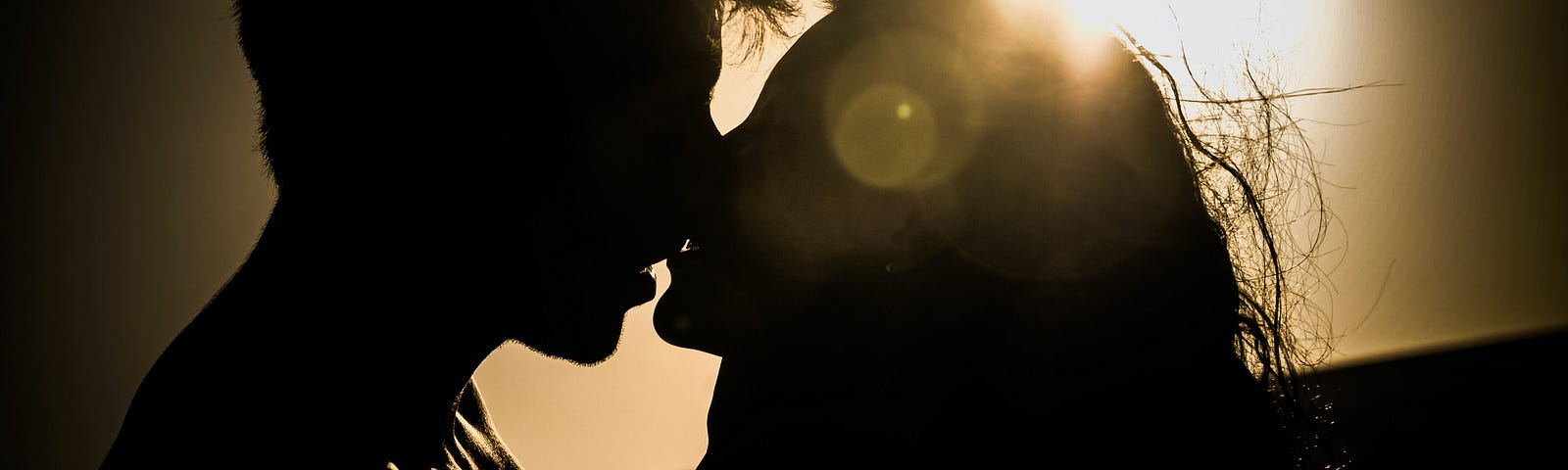 Silhouette of man and woman kissing.