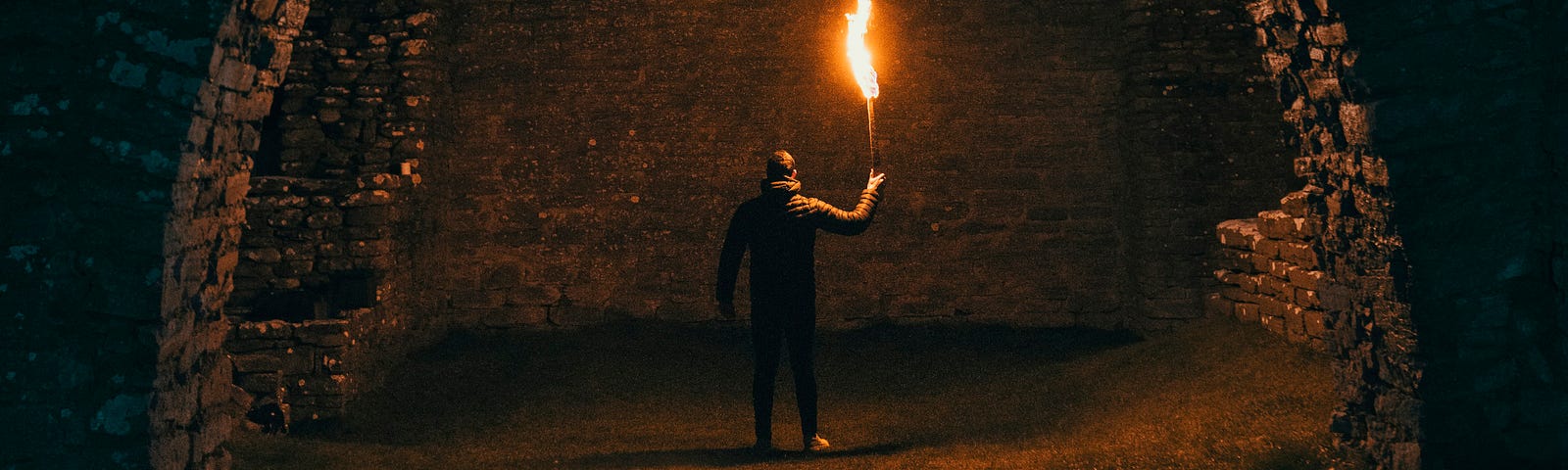 A figure holding a flaming torch in a tunnel