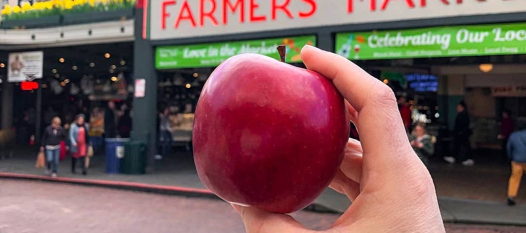 A Cosmic Crisp apple in front of a public market.