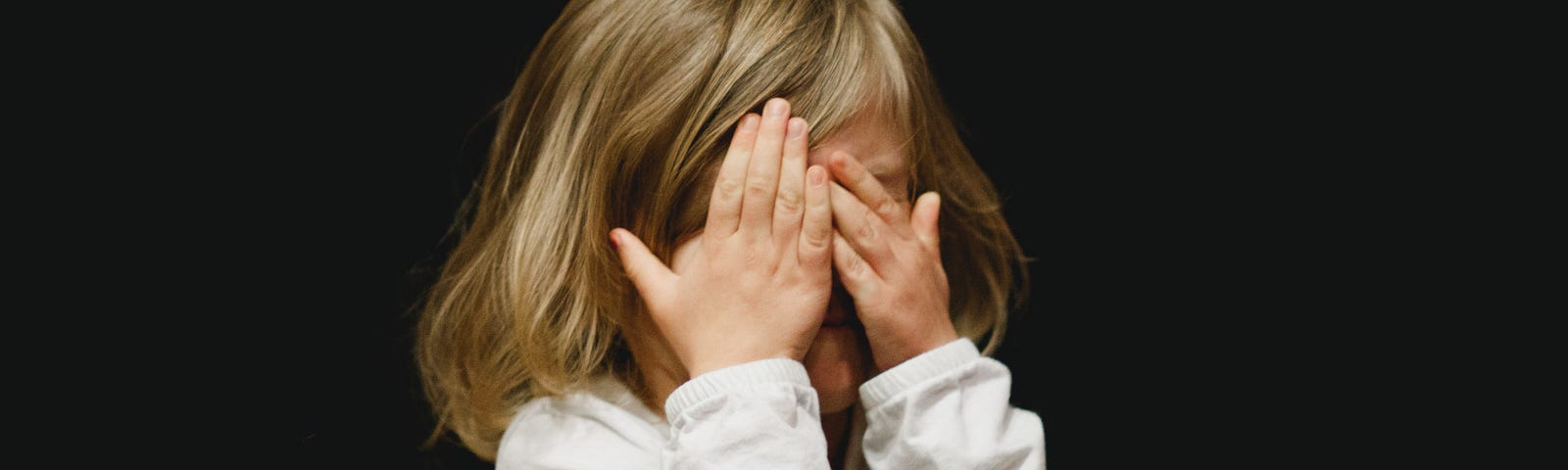 Girl covering her face with her hands.