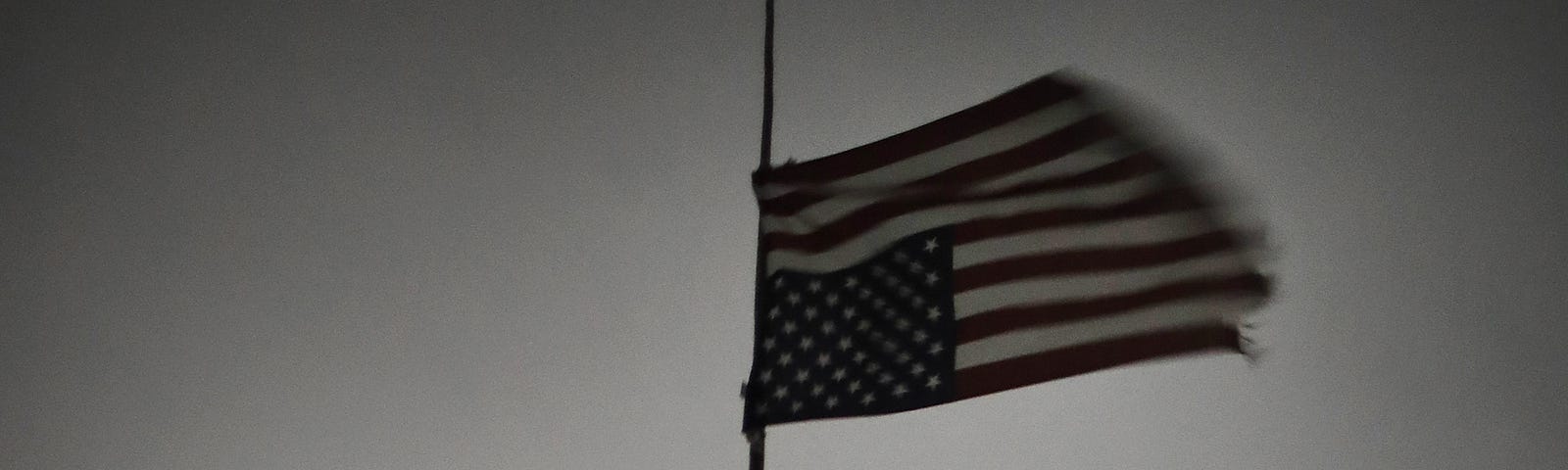 A photo of an upside down American flag hanging over a dark, ominous sky in Oceti Sakowin Camp.