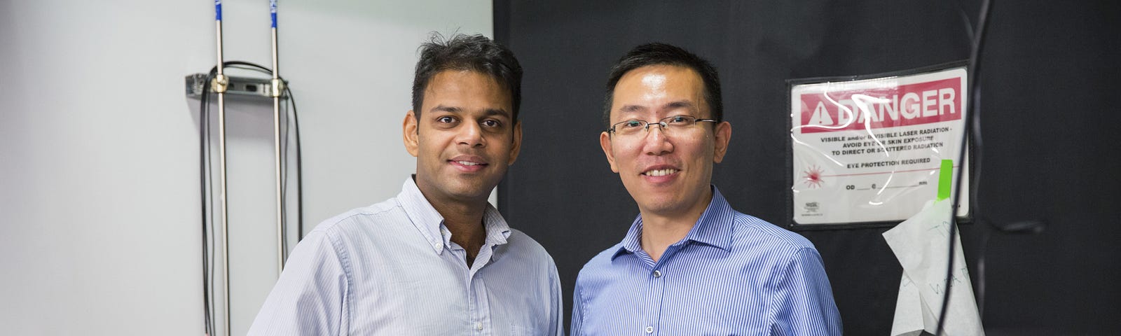 Ritesh Agarwal and Liang Feng pose among electrical engineering equipment.