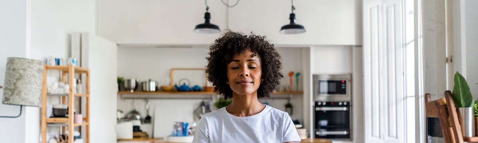 A photo of a black woman meditating while sitting on top of her table.