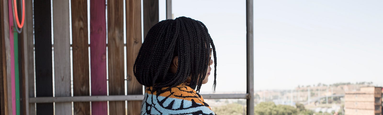 A photo of a young woman on her balcony looking outside.