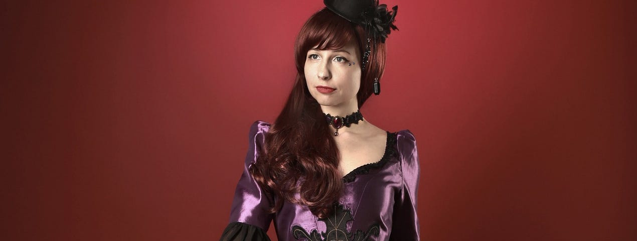 Young woman in formal, period dress, purple satin, black lace, Victorian style, gothic, wears a small riding hat and carries a silver topped cane, cosplay