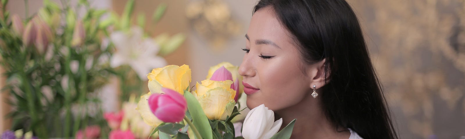 Woman smelling a bunch of tulips in a flower shop.