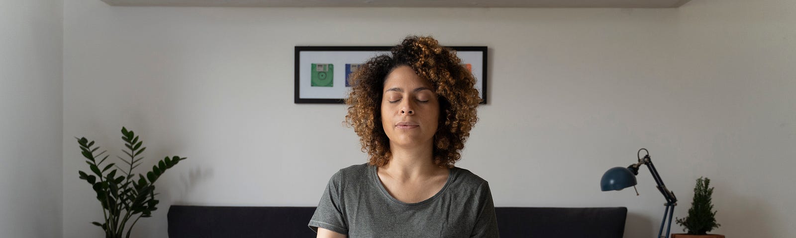 A woman sits on her bed and practices mindfulness through meditation.