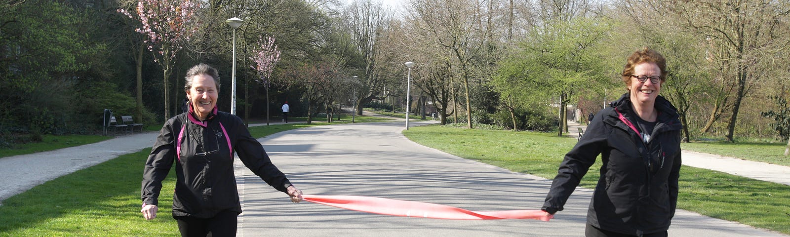 Two women holding a pink scarf practice social distancing and keep 1.5 meters at the park on March 27, 2020 in Amsterdam.