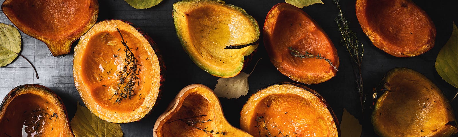 Halved, roasted pumpkins and butternut squash on a black surface.