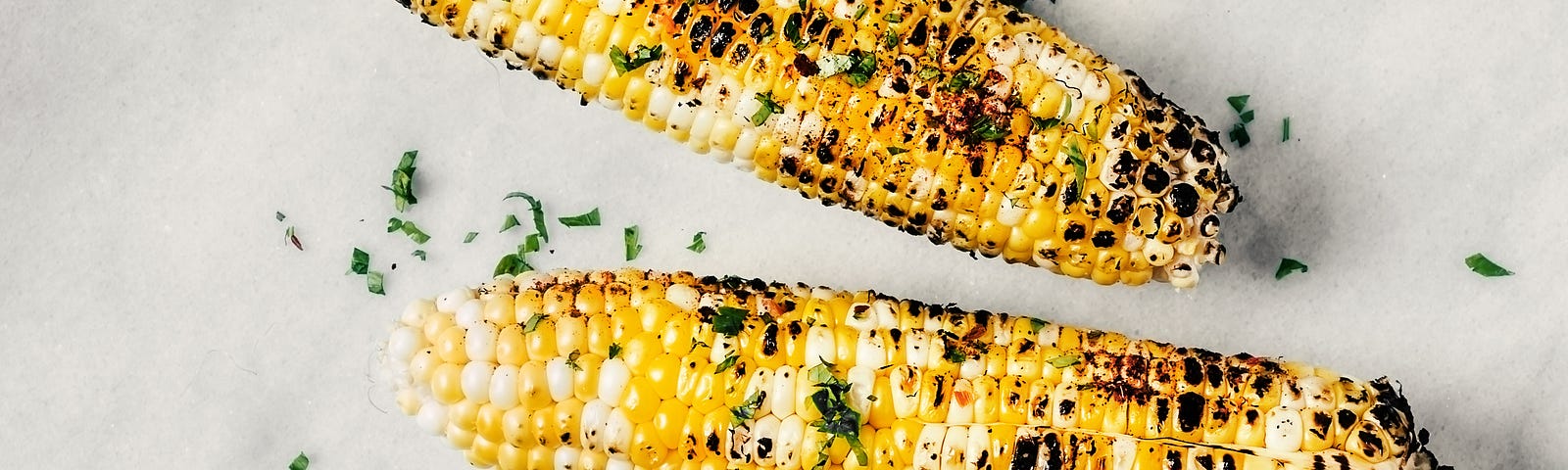 4 roasted ears of corn sprinkled with salt, pepper, parsley, and basil, and served with lemon wedges.