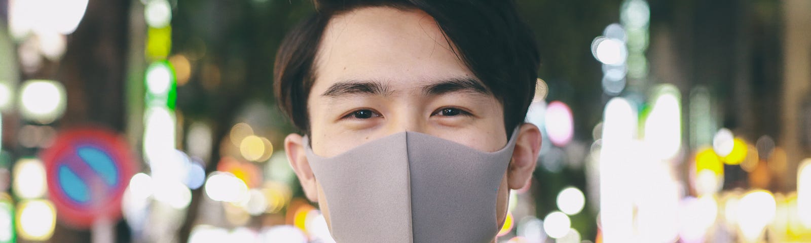 A man smiling while wearing a protective face mask.