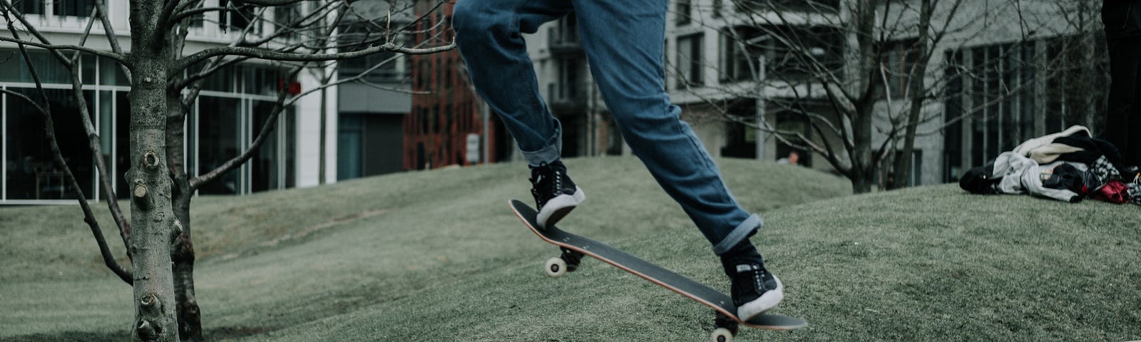 Low view of a teen doing a jump on a skateboard on the sidewalk.