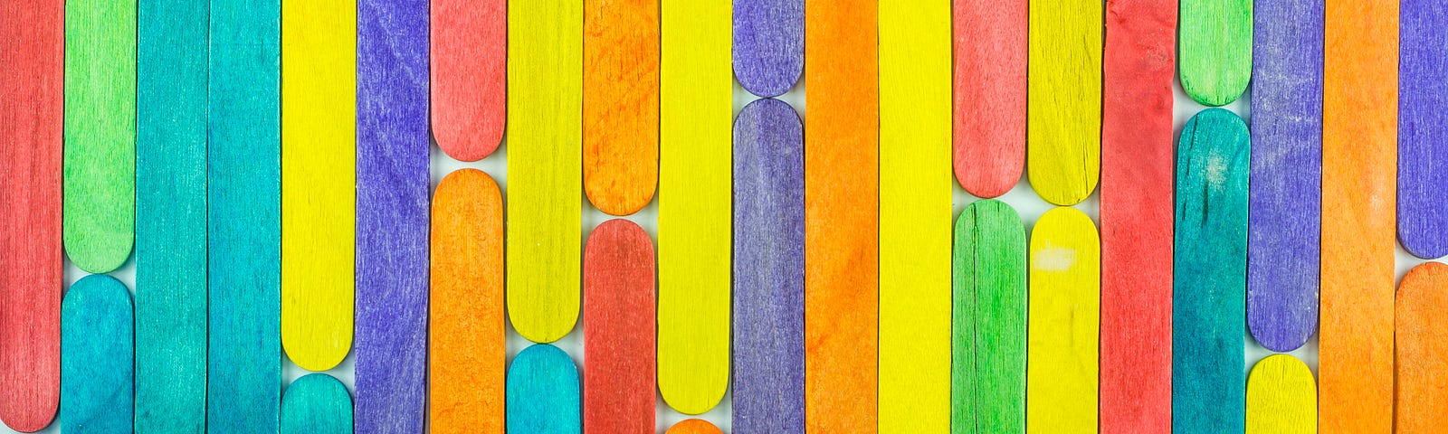 A photo of colorful popsicle sticks lined up to look like a wallpaper.