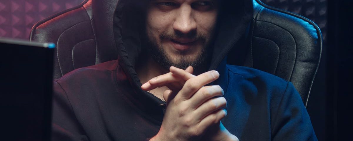 Bearded man in a hoodie sitting in front of his computer, rubbing his hands together.