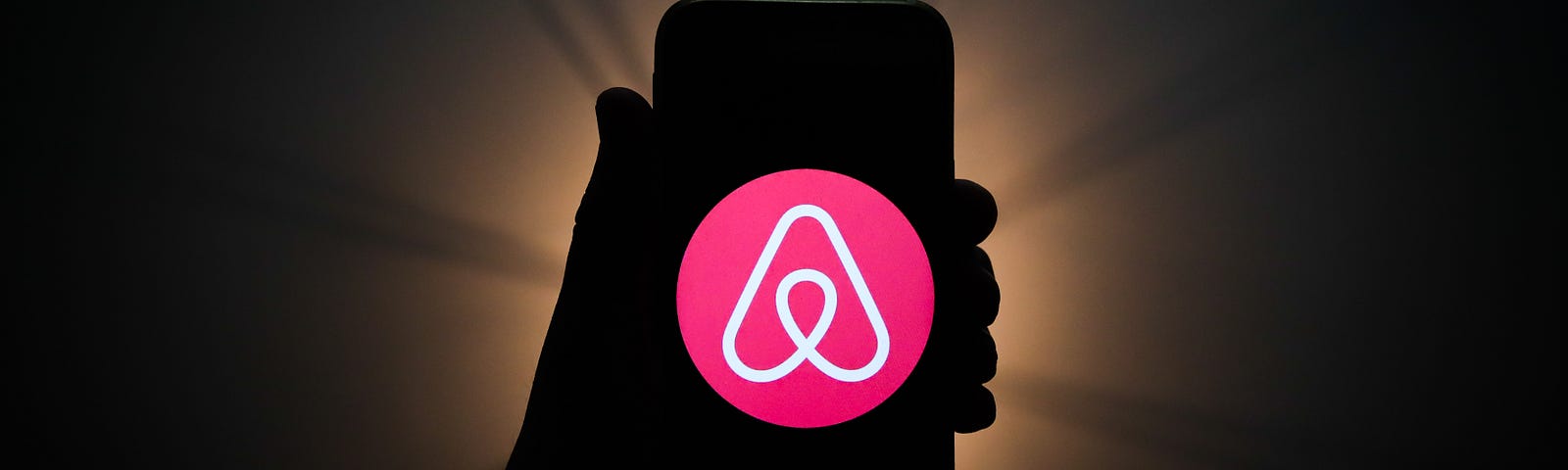 Airbnb logo is seen displayed on a phone screen