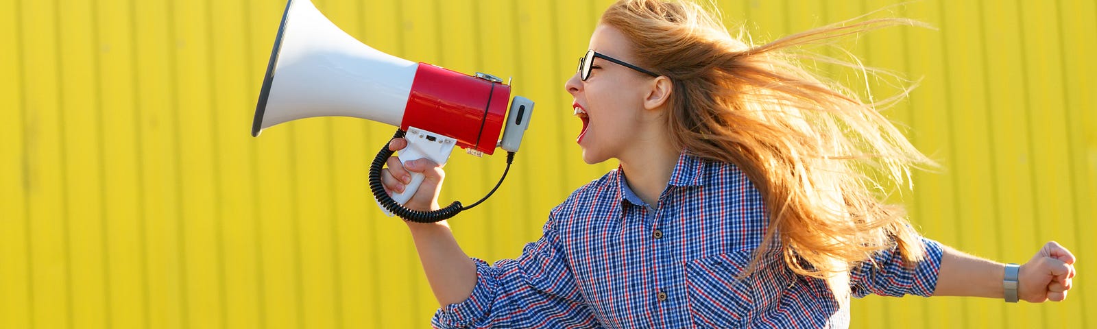 A person with long hair screaming into a megaphone.