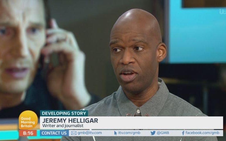 Still from a Good Morning Britain broadcast. Jeremy Heller, a Black man with a shaved head, above a chyron that says: “Developing story. Jeremy Helligar: Writer and journalist,” and in front of a blurred photo of a worried-looking Liam Neeson holding a cellphone to his ear.