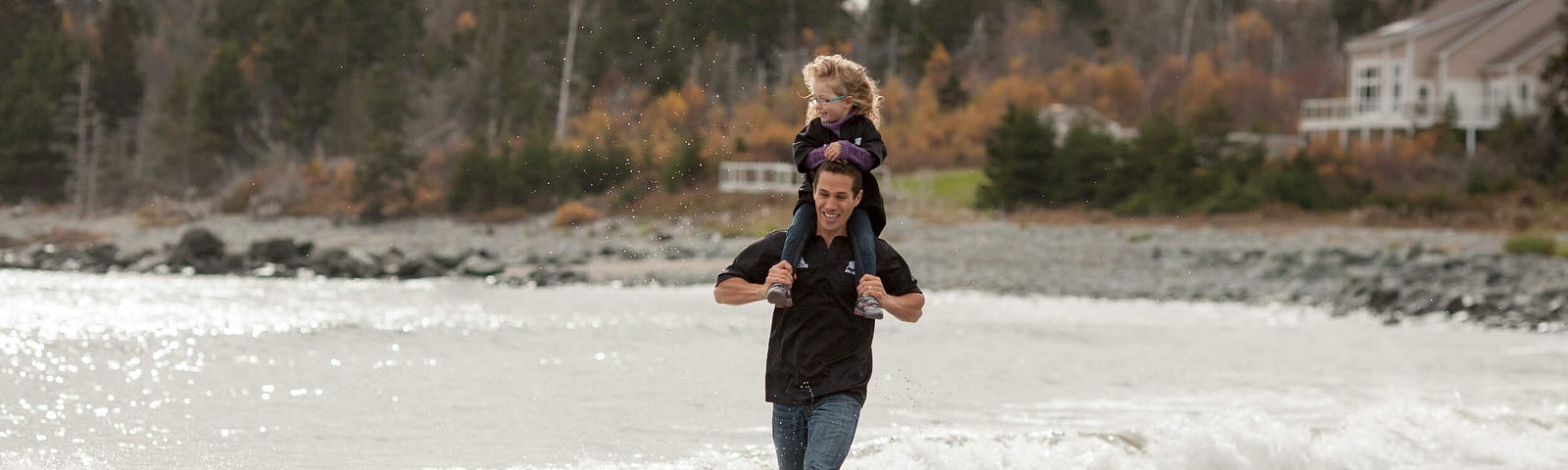 Author with his daughter on his shoulders running in the surf on the beach