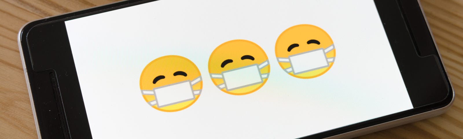 Emoticons with face masks on a phone screen.