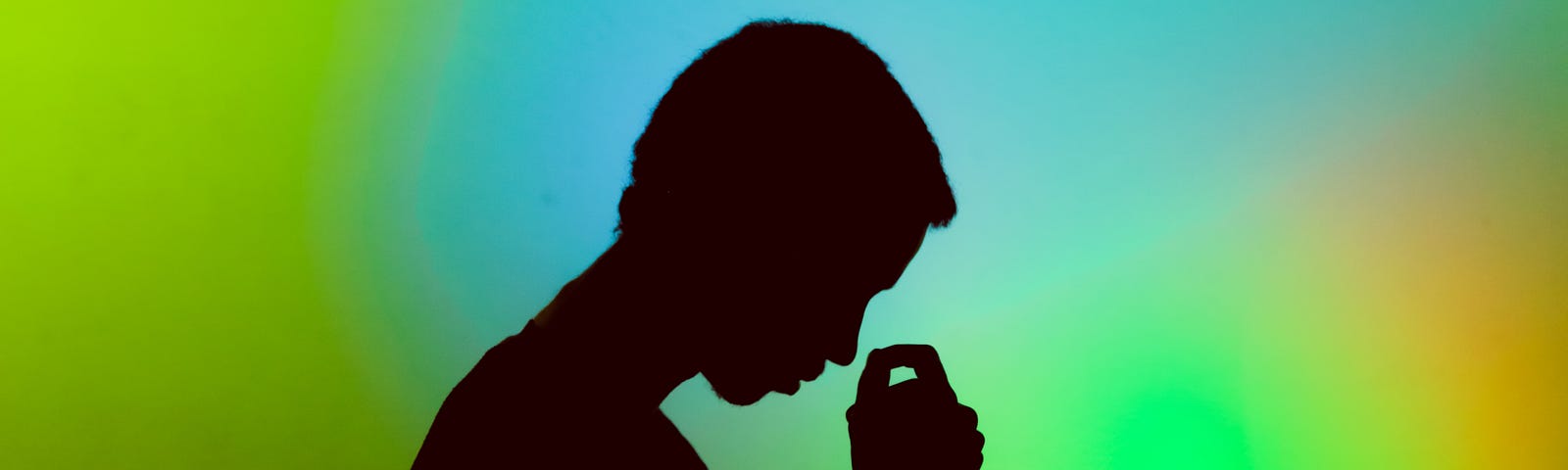 Silhouette of a young person bringing their hand up to cover their face