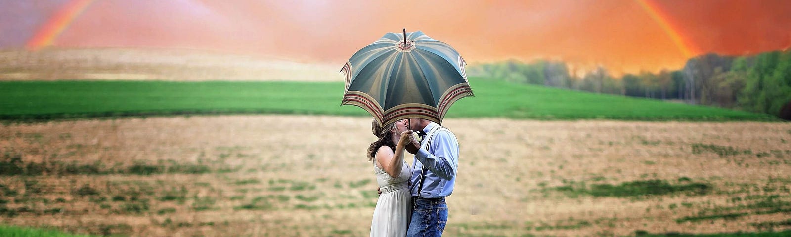 Evoking the concept behind Finneas debut album ‘Optimist’, the image shows a couple kissing on a field under an umbrella with a rainbow in the background