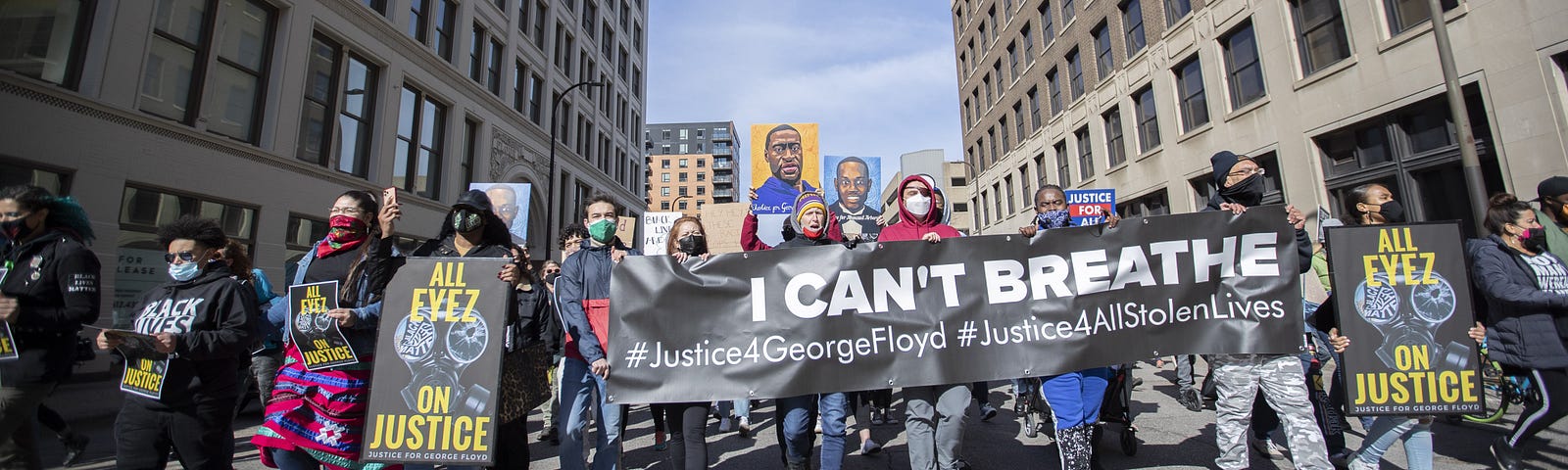 Protestors hold signs saying “I can’t breathe” and “All Eyez on Justice”