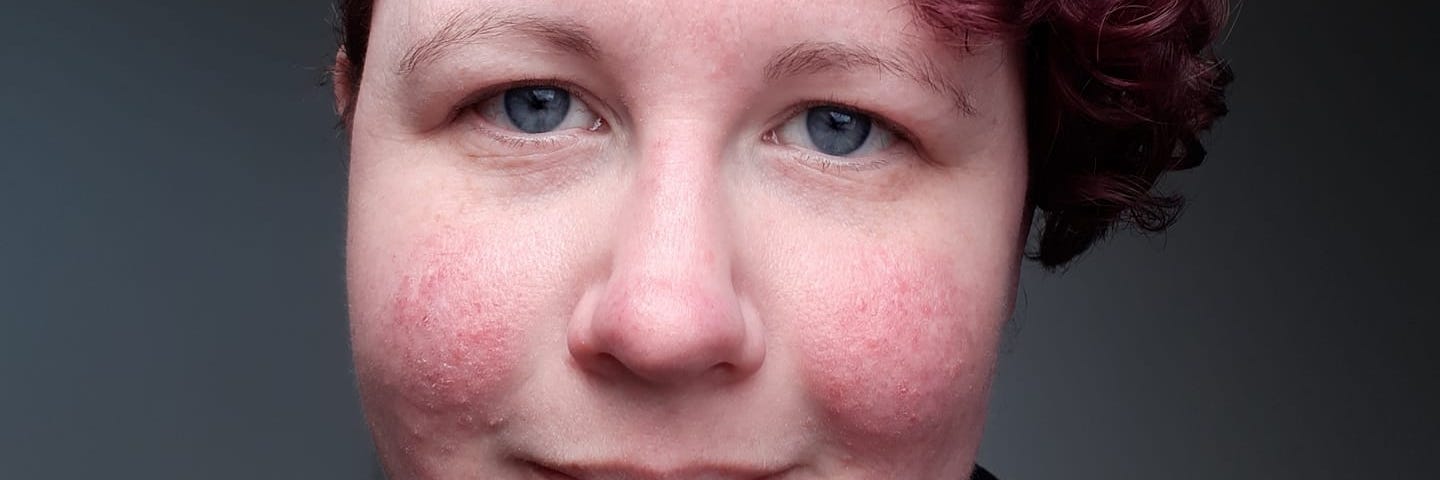 Kelley, the author, is pictured with a short curly pixie hairstyle. Her hair is curly and dyed a purple-maroon colour.