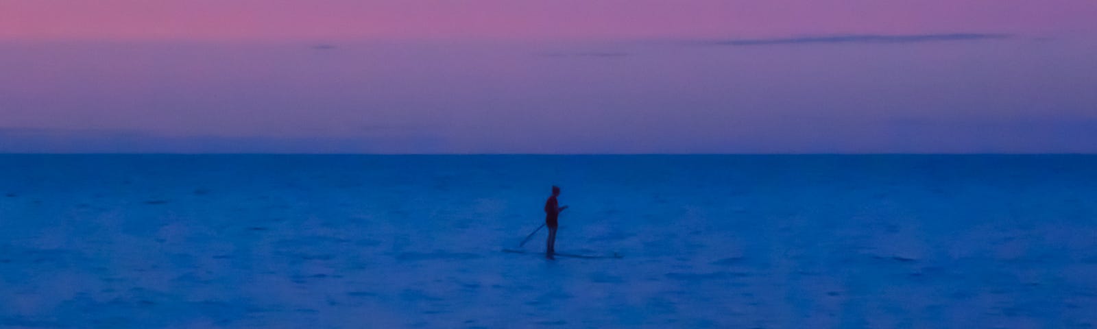Float—a paddle boarder gliding across the lake at blue-pink sunset sky | nature photography | © pockett dessert