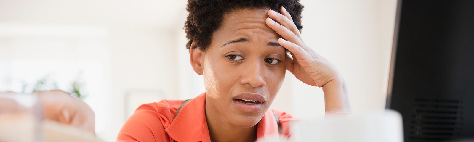 A photo of a frustrated black woman sitting at her desk at work.