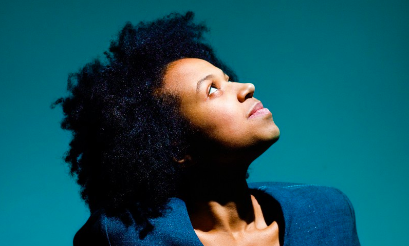 Black woman looking up against a teal background.