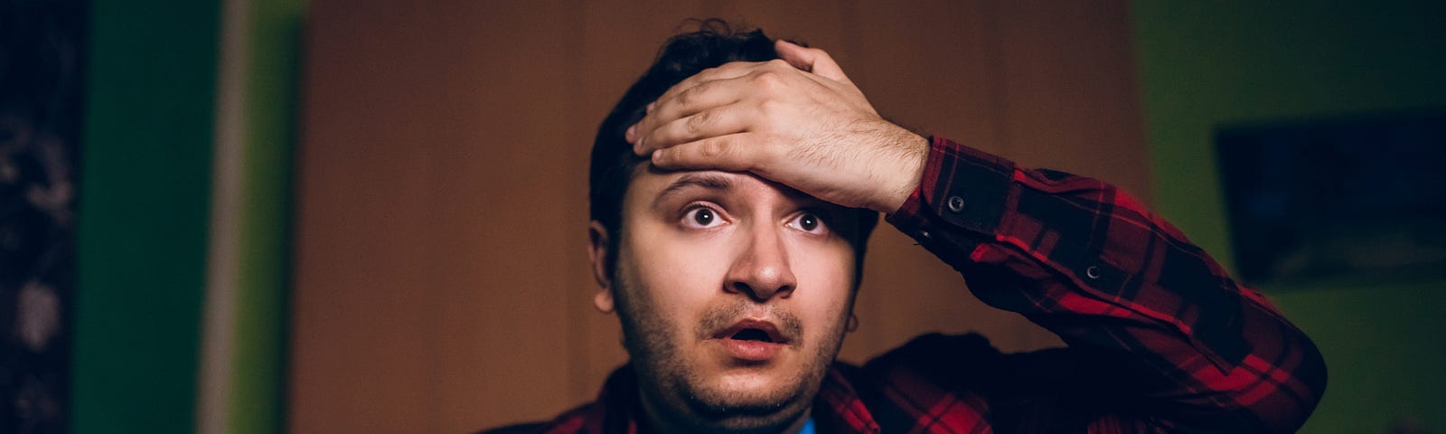 A young man, with his hand on his forehand, looks distressed.