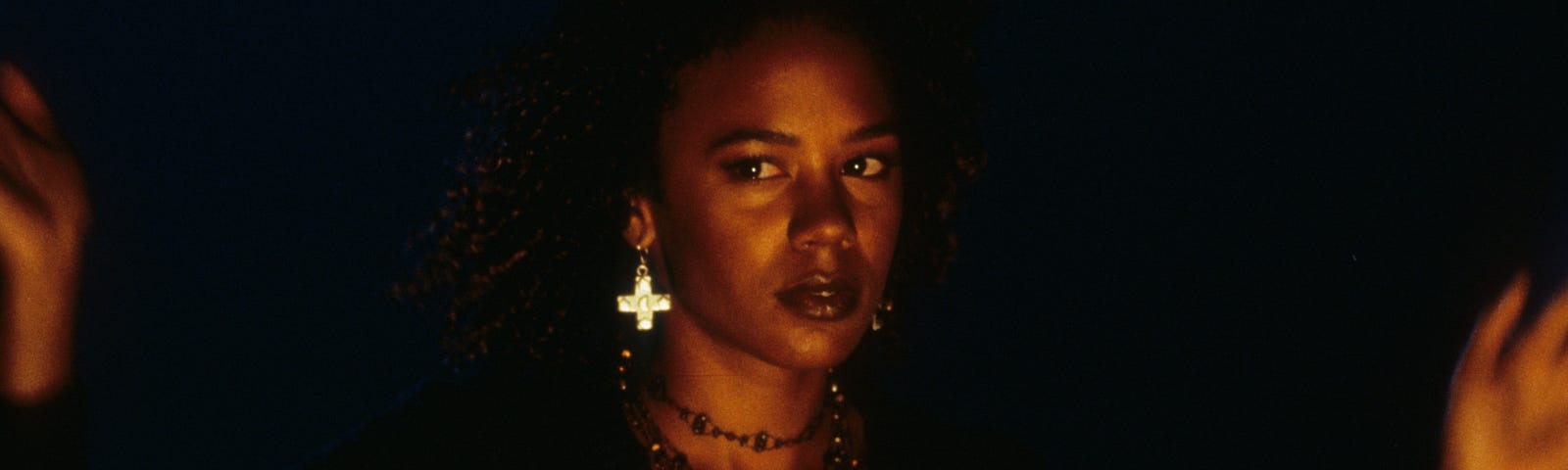 Screenshot of Rachel True from “The Craft.” She is wearing black and many necklaces.