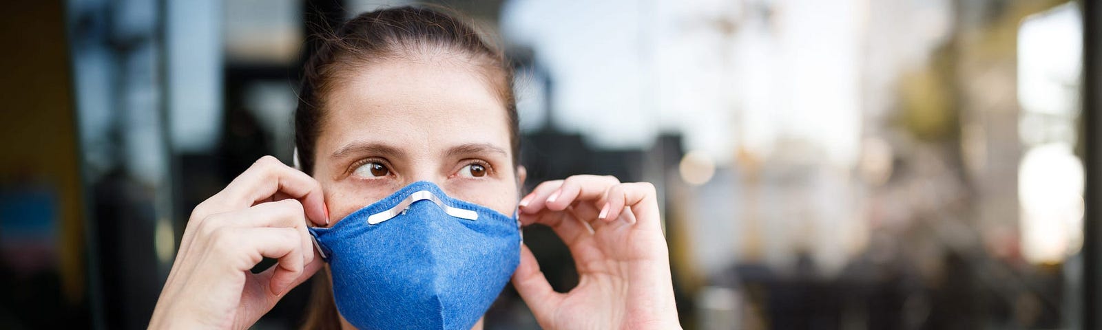 A woman adjusts her face mask.