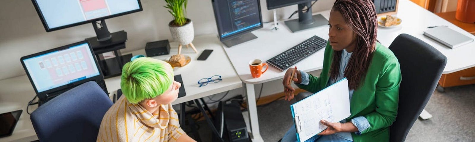 Two people sitting in an office talking.