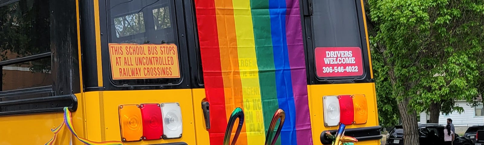 A yellow school bus with a rainbow Pride flag on the back and the word “celebrate” in rainbow letters across the back.