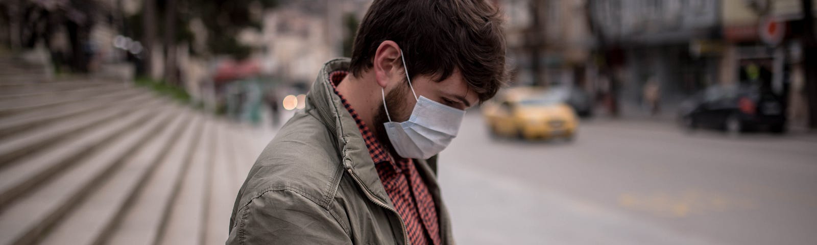 A man wearing a face mask types into his phone.