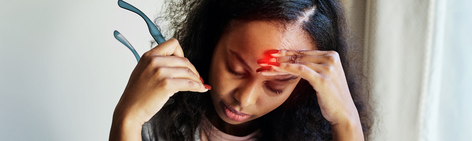 Shot of a young woman suffering from a headache while using a laptop at home.