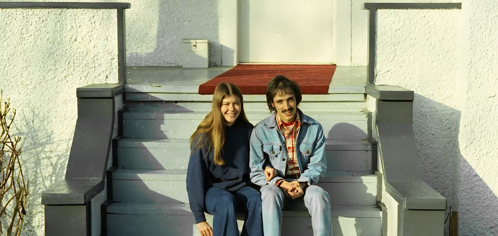 A couple sitting on the front steps of a house