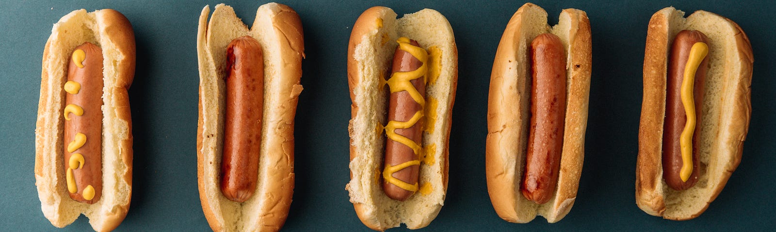 Five hot dogs against a blue background