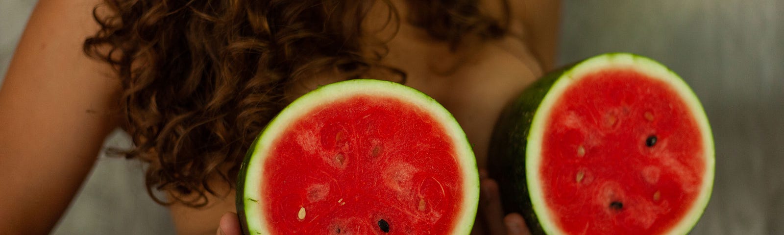 Woman holding up watermelons to her breasts