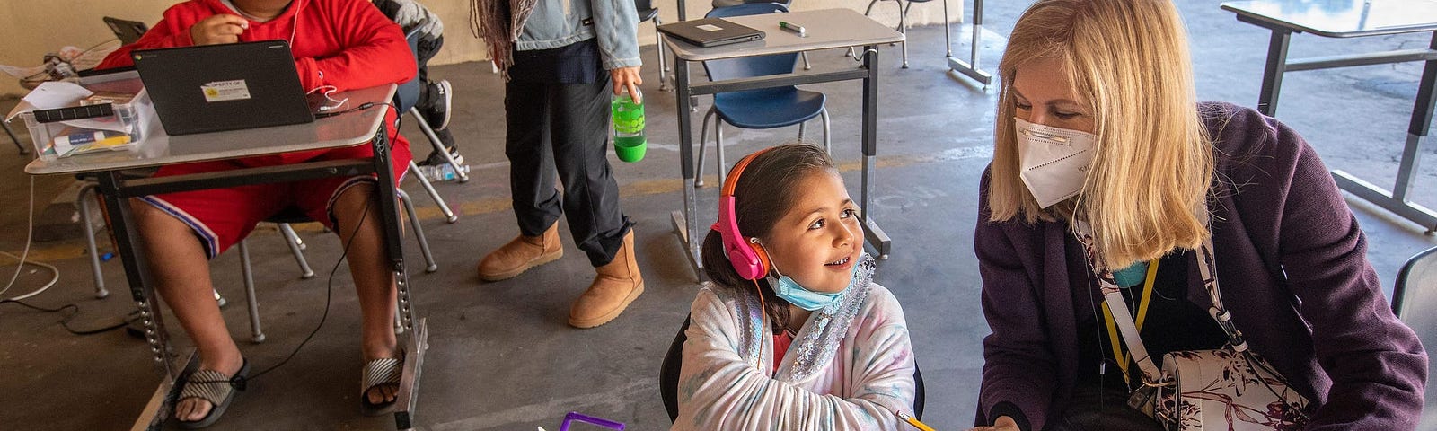 Volunteers help students at a learning pod for homeless children in California.