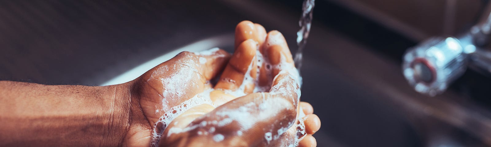 A close up hand washing in the kitchen sink.