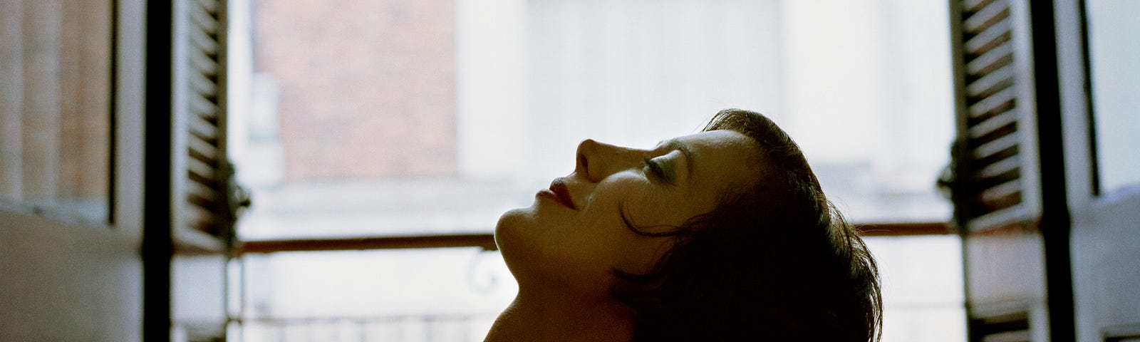 Woman leaning her head back, eyes closed, with a peaceful look.