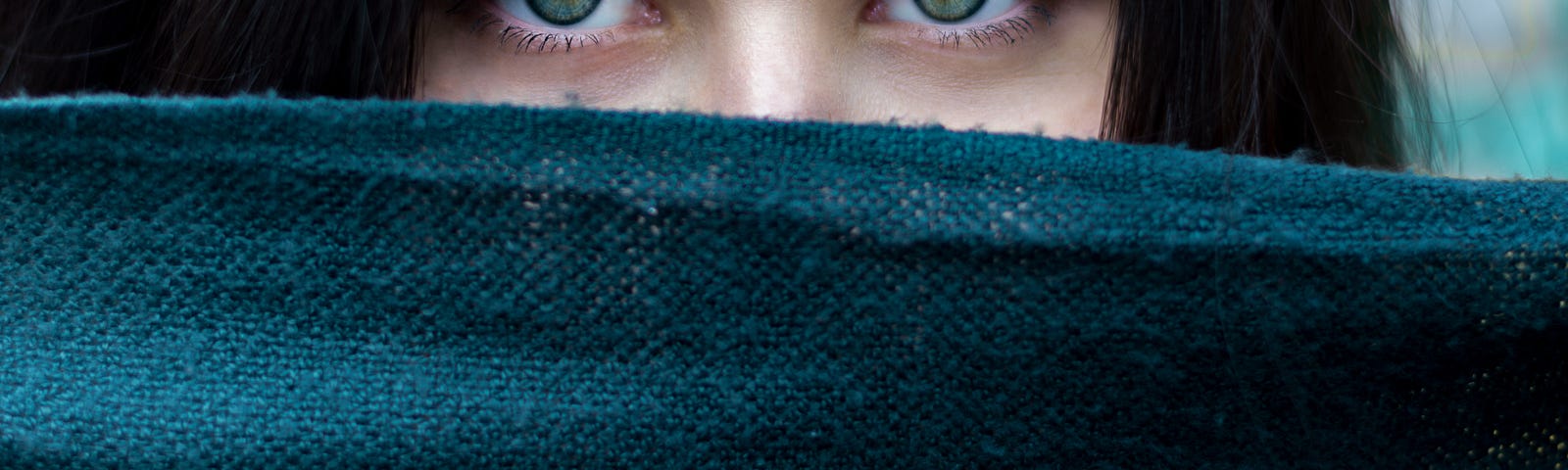 girl peering over the edge of a cloth