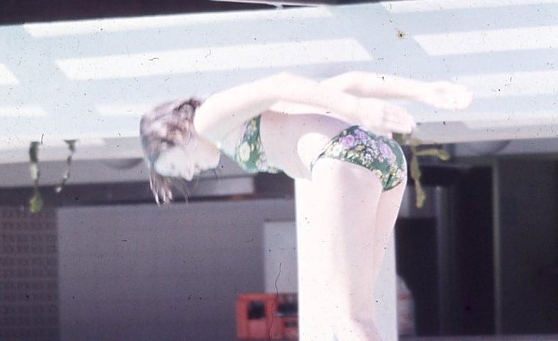 teen aged girl in a green bikini diving into a pool