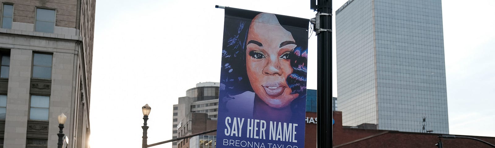 A street banner with an image of Breonna that says “SAY HER NAME BREONNA TAYLOR #BREEWAYY.”