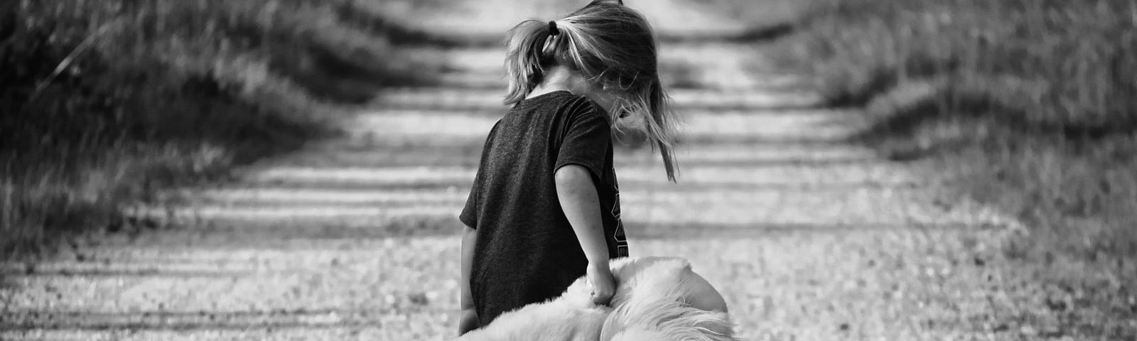 A black and white image of a little girl holding a plush toy and walking away on a dirt road.