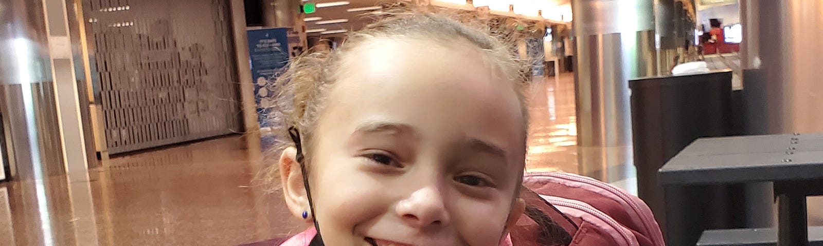 Young girl smiling and with backpack on waiting to take her first flight.