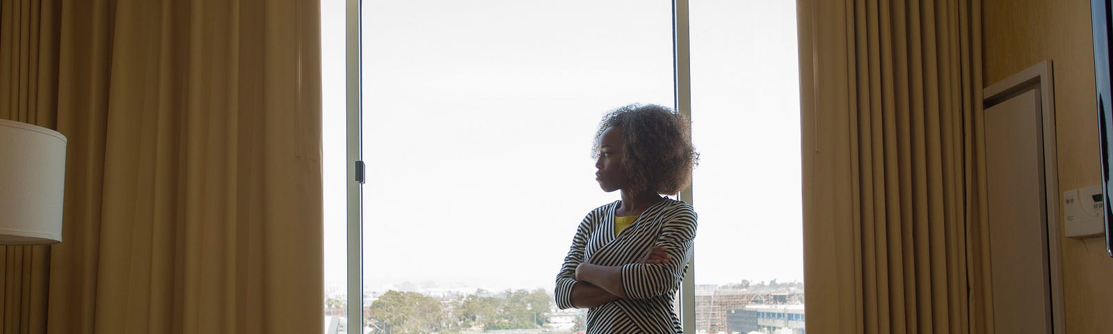 A photo of an unhappy black woman looking out the window.