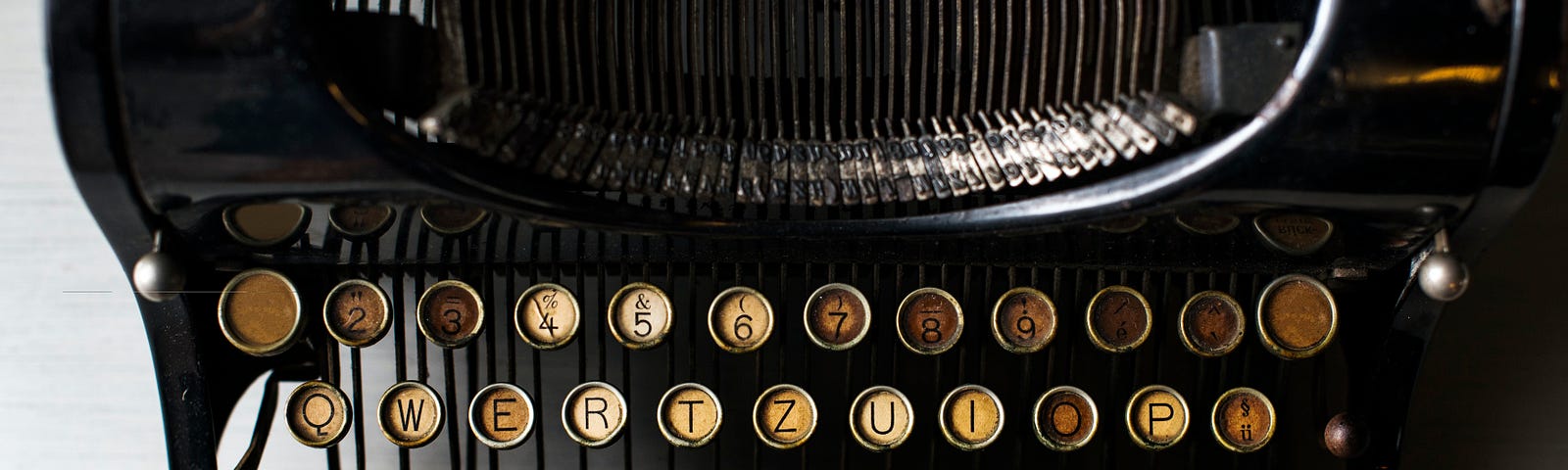 An antique black typewriter with aged yellow keys.